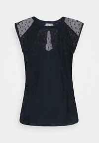 Marinblå t-shirt med spetspaneler och genomskinliga mesh-kapsleeve. Har intrikata blomstermönster längs sidorna. Mjuk, figurnära textur.