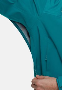 Turkusowa wodoodporna kurtka z zamykaną na zamek kieszenią, regulowanymi sznurkami i teksturowanym panelem. Charakteryzuje się eleganckim designem i lekką konstrukcją.