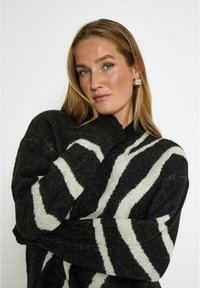 Schwarz-weißer gestreifter Strickpullover mit gerippten Bündchen und Kragen. Weicher Stoff und lockerer Schnitt, mit auffälligen diagonalen Streifen.