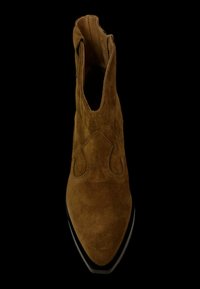 Bota de vaquero de ante marrón con punta afilada, costuras decorativas y lengüetas de agarre en el cuello en forma de S, sobre fondo negro.
