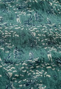 Tessuto in cotone con stampa nautica. Presenta illustrazioni blu di marinai, navi e rose dei venti su uno sfondo verde acqua con motivi ondulati.