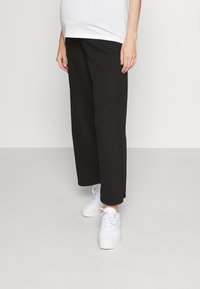 Mustat leveälahkeiset housut, jotka on valmistettu pehmeästä kankaasta ja joissa on rento istuvuus sekä sivusaumat. Yhdistetty valkoisiin korkokenkiin.