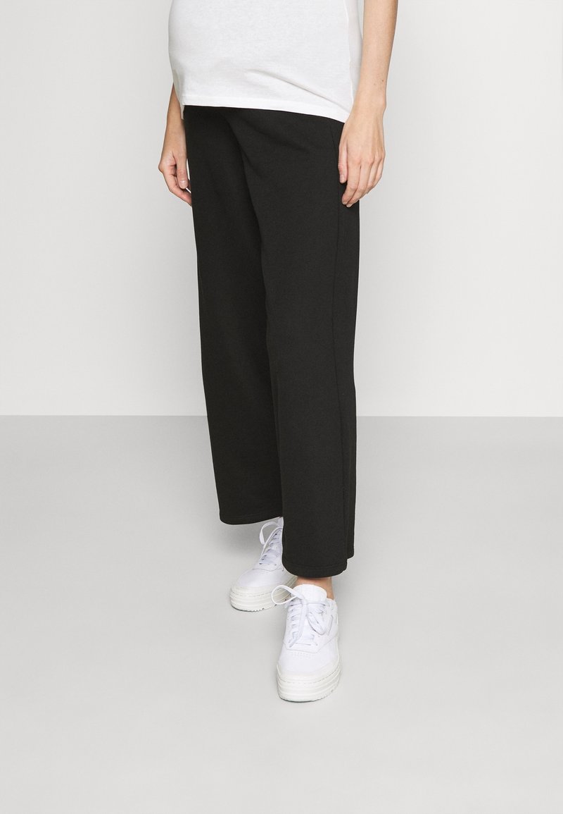 Mustat leveälahkeiset housut, jotka on valmistettu pehmeästä kankaasta ja joissa on rento istuvuus sekä sivusaumat. Yhdistetty valkoisiin korkokenkiin.