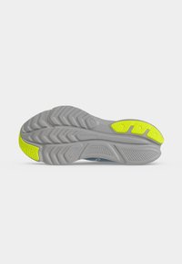 Semelle de chaussure avec empreinte grise et coussinets de préhension jaunes au talon et à l’orteil, avec motifs texturés et nom de la marque "Saucony" au centre.