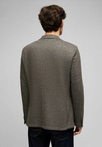 Grau strukturiertes Blazer aus Wolle, mit Reverskragen, geradem Saum und geknöpften Manschetten. Trägt man über einer dunklen Jeans.