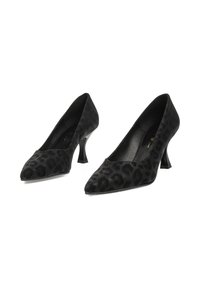 Tacones negros con puntera afilada y un pequeño tacón curvado. Hechos de un material texturizado que presenta un sutil estampado de leopardo.