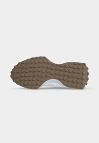 Semelle de chaussure avec semelle extérieure en caoutchouc marron présentant des picots ronds antidérapants, un support visible de la voûte plantaire et une section intermédiaire blanche.