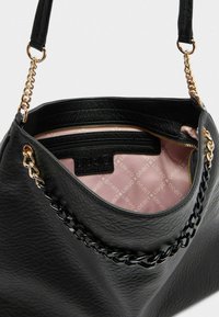 Sac à main en simili cuir noir avec une surface texturée, des accents en chaîne et une doublure intérieure rose ornée d'un motif logo. Comprend une poche zippée.