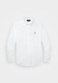 Vit skjorta med knappar som har klassisk krage, långa ärmar och en liten broderad logotyp på vänster bröst. Tillverkad av bomullstyg med en jämn textur.