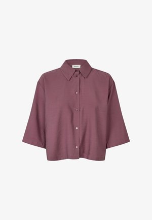 Chemise boutonnée en mauve doux avec col large et manches trois-quarts, présentant une coupe carrée et courte.
