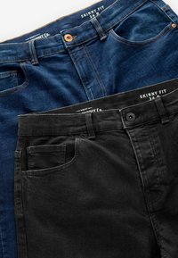 Jeans skinny en denim foncé et coton noir. Les caractéristiques comprennent des coutures contrastantes, des poches avant et des ceintures de marque.