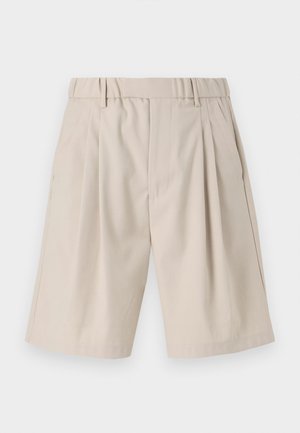 Beżowe szorty z plisami wykonane z gładkiego materiału, z paskiem z pętelkami oraz kieszeniami bocznymi. Klasyczny prosty krój, długość do kolan.