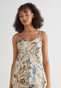 Beige satijnen camisole met een blauw en bruin bloemenpatroon, voorzien van dunne verstelbare bandjes en een V-halsontwerp. Gladde textuur.