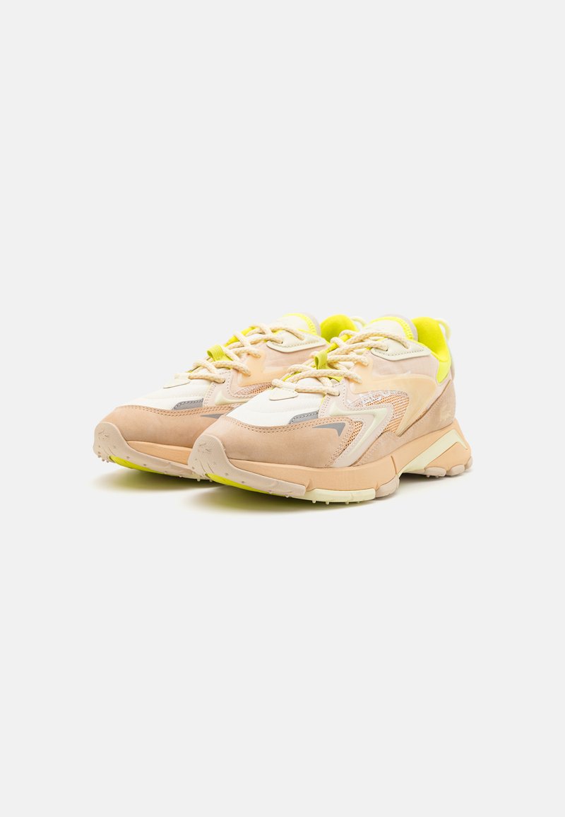 Sneakers met een licht perzikkleurige en crèmekleurige bovenkant, neon gele accenten, meshpanelen en een chunky zool met een gestructureerde grip.