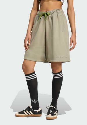 Olive green sweat shorts with a drawstring, side pockets, and subtle logo embroidery. Paired with black knee-high socks featuring white stripes.