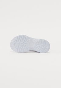 Semelle de chaussure en caoutchouc blanc avec des motifs de semelle texturés et un emblème central en forme de cercle, présentant des lignes courbes et des rainures pour une meilleure adhérence.