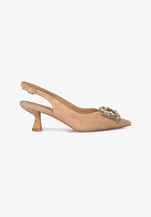 Zapato slingback de ante beige con punta afilada, tacón bajo en bloque y un detalle decorativo embellecido con gemas en la parte frontal.