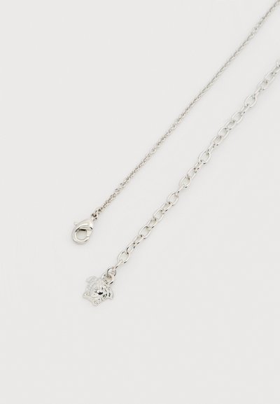 Ασημένιο κολιέ με κούμπωμα σε σχήμα αστακού, λεπτή αλυσίδα και μενταγιόν με περίτεχνες λεπτομέρειες λιονταριού και μικρή διακοσμητική πέτρα ρίνστοουν.