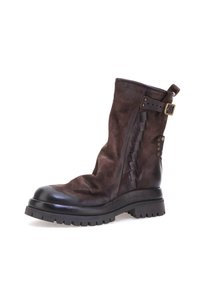 Botín de cuero marrón oscuro con suela negra, correa de hebilla lateral, detalles de costura y suela texturizada y con relieve.