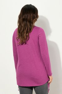 Pitkähihaisessa violetissa paidassa on pehmeä kangas, sivu.php-solmut, rento istuvuus ja pyöristetty helma.