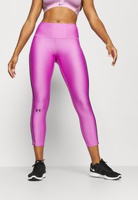 Rosa, högmidjade leggings gjorda av glansigt, stretchigt material med svarta sidostripes och en liten logotyp på vänster ben, i kombination med svarta sneakers.