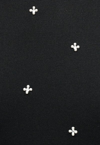 Μαύρο υφασμάτινο με υφή,  διακοσμημένο με μικρές ομάδες λευκών χαντρών που σχηματίζουν σταυρούς διασκορπισμένους στην επιφάνεια.