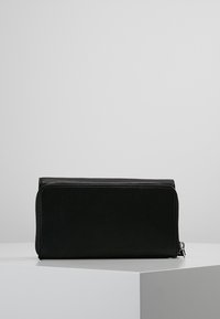 Czarny skórzany portfel o fakturowanej powierzchni, prostokątnym kształcie, zamykany na zamek błyskawiczny, z kontrastującym białym przeszyciem wzdłuż krawędzi.