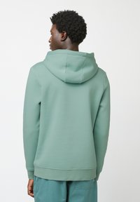 Lichtgroene hoodie met een buideltas, geribbelde manchetten en zoom. Zacht, gestructureerd stof, naadloze capuchon aan de achterkant bevestigd.