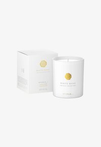 Duftlys i en hvit glassbeholder med et gyllent emblem. Inkluderer en hvit boks merket "Hvit Basilikum" med produktinformasjon i gull og svart.