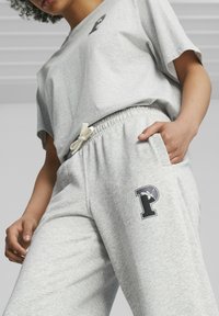 Conjunto de ropa activa de mezcla de algodón gris que incluye una camiseta de corte holgado con un logo y pantalones jogger a juego con cinturilla elástica y bolsillos laterales.