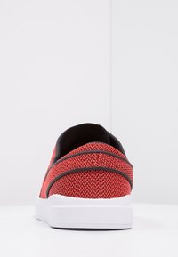 Baskets rouges tissées avec une tige en tissu texturé, des accents noirs et une semelle en caoutchouc blanche. Design profil bas avec un bout arrondi.