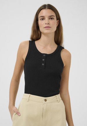 Top de tirantes negro con canalé, escote redondeado y tres botones en la parte delantera. La tela es suave y tiene una forma ajustada. Se combina con pantalones beige de cintura alta.