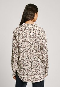 Camicia con bottoni caratterizzata da un intricato motivo floreale in vari colori su uno sfondo chiaro, realizzata in un tessuto morbido, con maniche lunghe e una vestibilità comoda.