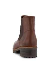 Hnědé kožené kotníkové boty s elastickými bočními panely, texturovanou podrážkou a nízkým blokovým podpatkem. Vlastnosti zahrnují logo blízko podpatku.