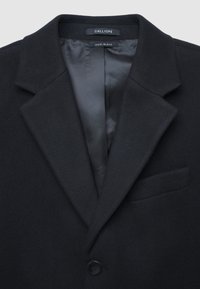 Cappotto in misto lana nero con rever a notched, singolo bottone nero, tasca sul petto e foderato in satin, etichettato Calliope.