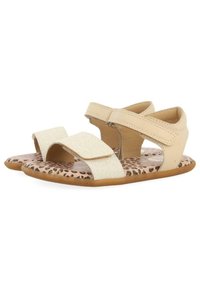 Sandalias de cuero con dos correas beige brillantes, con plantilla de estampado de leopardo y suela de goma marrón flexible.