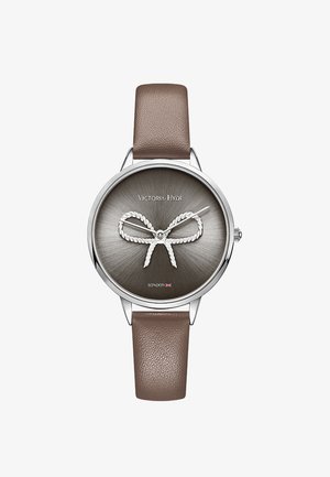 Montre ronde en acier argenté avec un cadran soleillé gris foncé, arborant un design en ruban. Bracelet en cuir brun et style minimaliste.