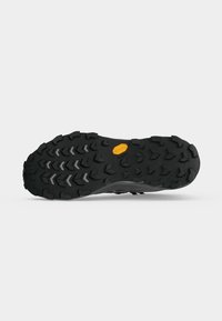 Semelle noire robuste pour chaussure de randonnée avec des crampons multidirectionnels profonds et un logo Vibram jaune près du centre.