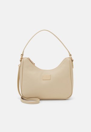 Beige handbag made from smooth synthetic material, featuring a curved shape, a short handle, and a detachable long strap. Gold hardware accents.