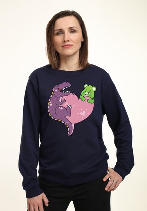 Marineblå sweatshirt med et trykt design af en lilla dinosaur og en grøn bjørn på et pink hjerte, lavet af blødt stof med lange ærmer.