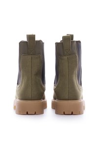 Botas Chelsea verdes y negras de material de lona y goma, con una suela robusta, paneles laterales elásticos y tiradores en la parte trasera.