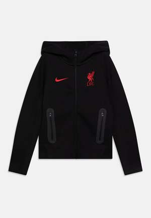 Veste zippée noire avec capuche, logo Nike rouge et écusson de Liverpool FC. Comprend deux poches latérales zippées et un tissu texturé.
