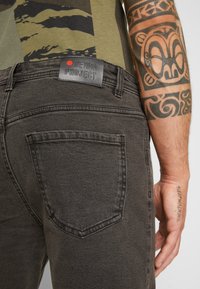 Čierne džíny z denimu s textúrovaným povrchom, s jednou zadnou vreckom a koženou nášivkou s nápisom "DENIM PROJECT."