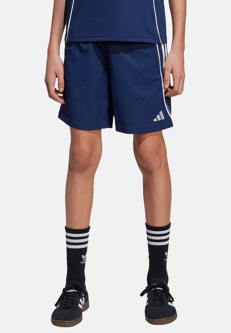Marinefarbene Sportshorts mit strukturiertem Design, adidas-Logo, weißen Seitenstreifen, kombiniert mit schwarzen gestreiften Socken und schwarzen Turnschuhen.