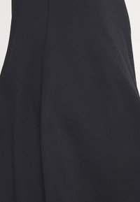 Gros plan sur un tissu noir avec des plis discrets et une texture lisse et douce.