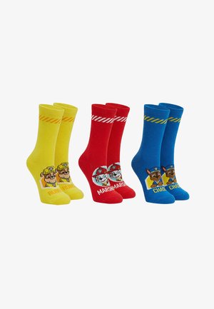 Drie paar kindersokken in geel, rood en blauw, elk met Paw Patrol-figuren Rubble, Marshall en Chase.