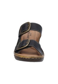 Sort lædersandal med glidende design, to brede stropper med messing spænder, stikninger og en tan farvet polstret sål. Flad gummisål.