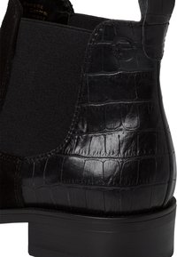 Stivaletto nero con tacco in pelle goffrata effetto coccodrillo, sopra in suede opaco e pannelli laterali elasticizzati. Suola nera spessa.