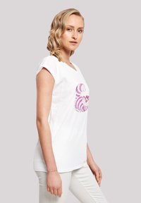 Hvit bomulls T-skjorte med korte ermer, med et fantasifullt lilla stripe-design og et grafisk bilde av en smilende katt. Glatt tekstur.