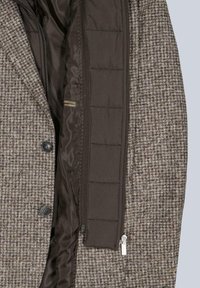 Brauner Mantel mit Hahnentrittmuster und dunklem, isolierendem Innenfutter, ausgestattet mit Reißverschluss und Knopfverschlüssen. Strukturierter Stoff mit glattem Innenbereich.